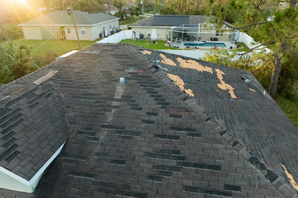 Aerial view of a roof with storm-damaged shingles and exposed underlayment